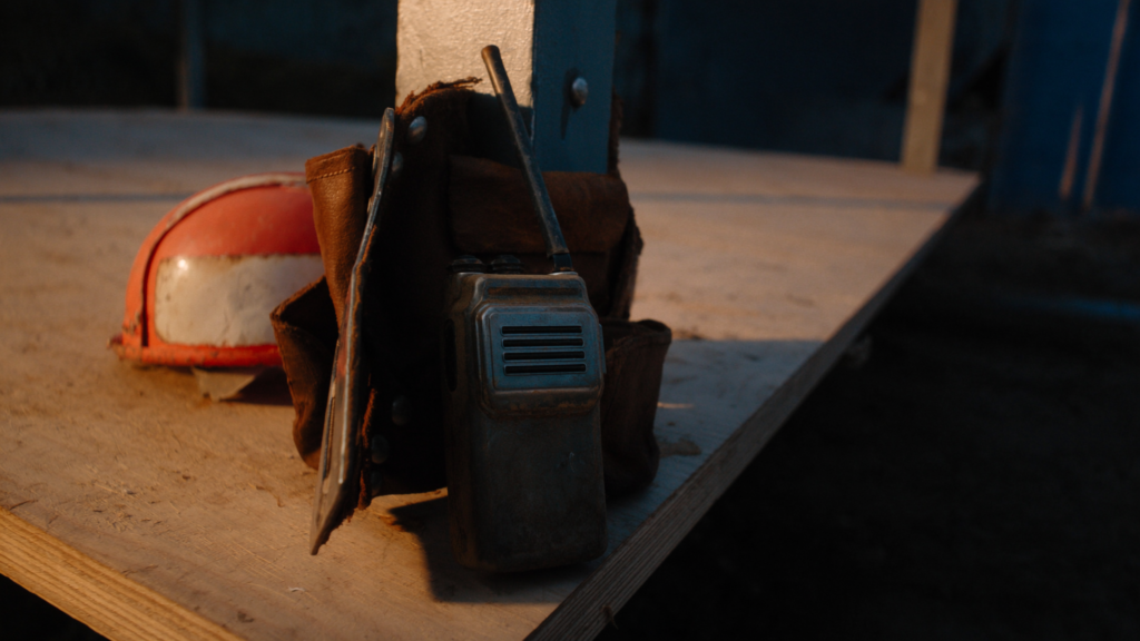 Two-way radio clipped to a dusty tool belt on a construction site at golden hour