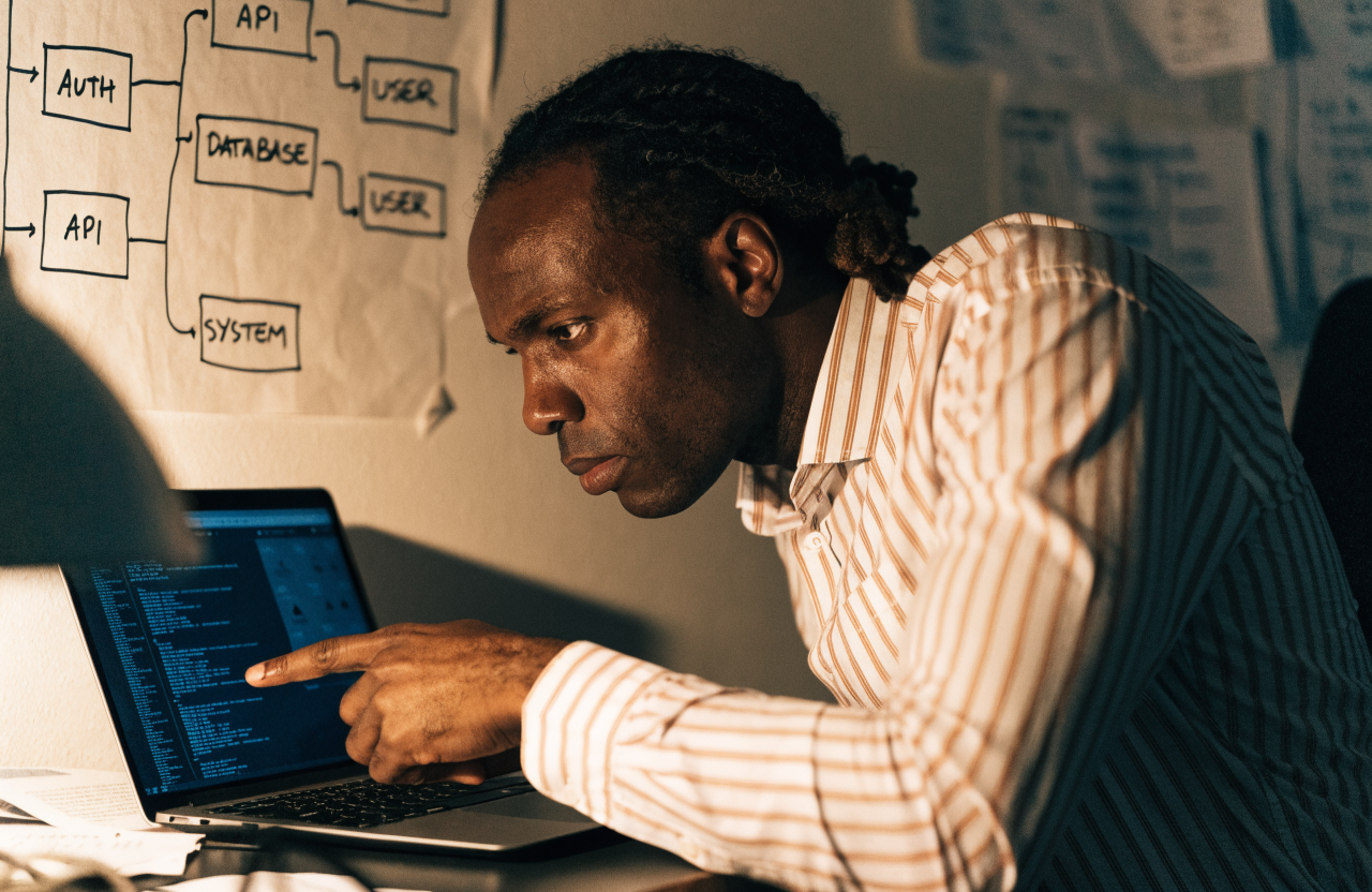 A man tracing a connection on a hand-drawn system flowchart on a wall