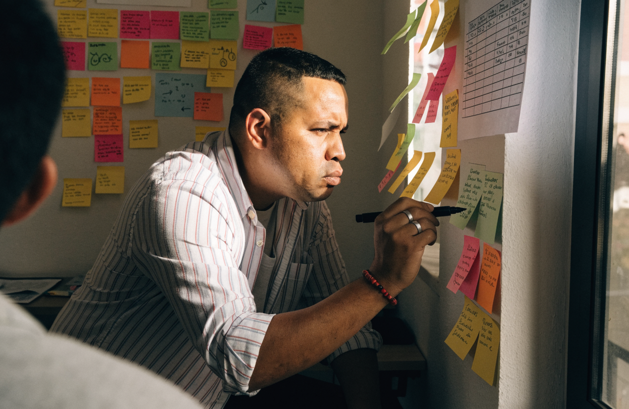 A man mapping a strategy across a wall of sticky notes