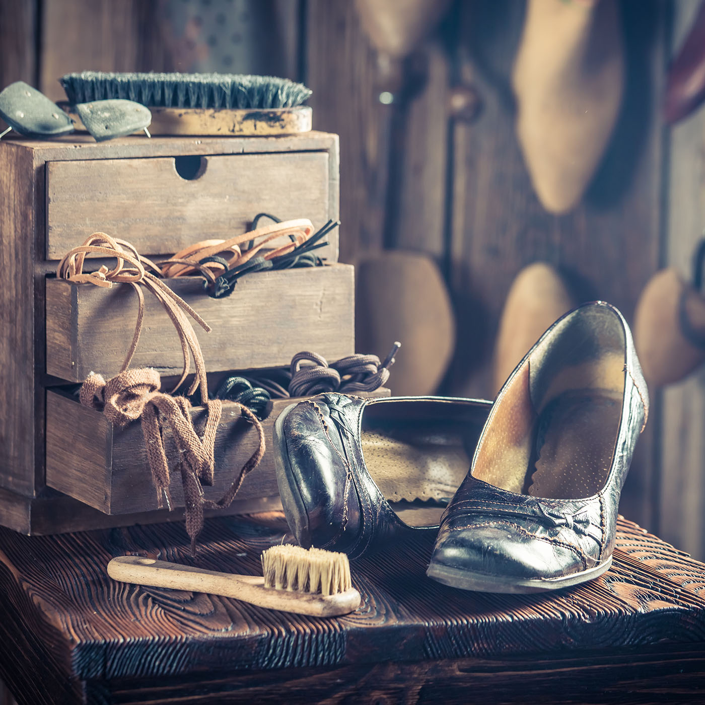 A shoemaker workshop bench covered in shoes, laces and hand tools