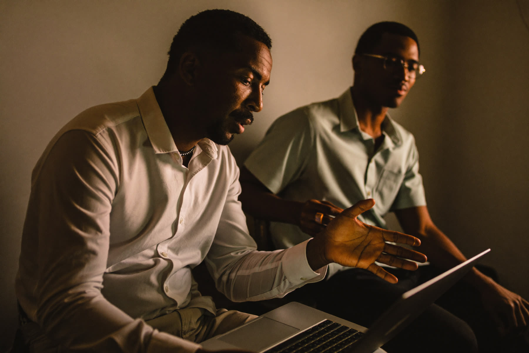 One man teaching another how to use a tool on a laptop