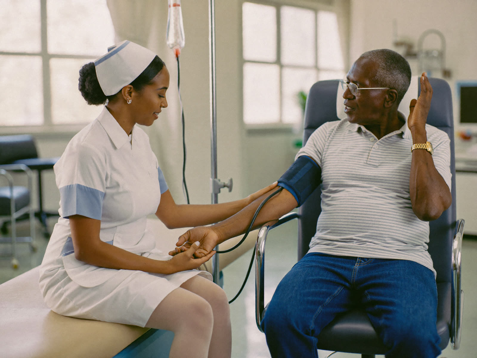 A nurse checking an older man blood pressure at a clinic