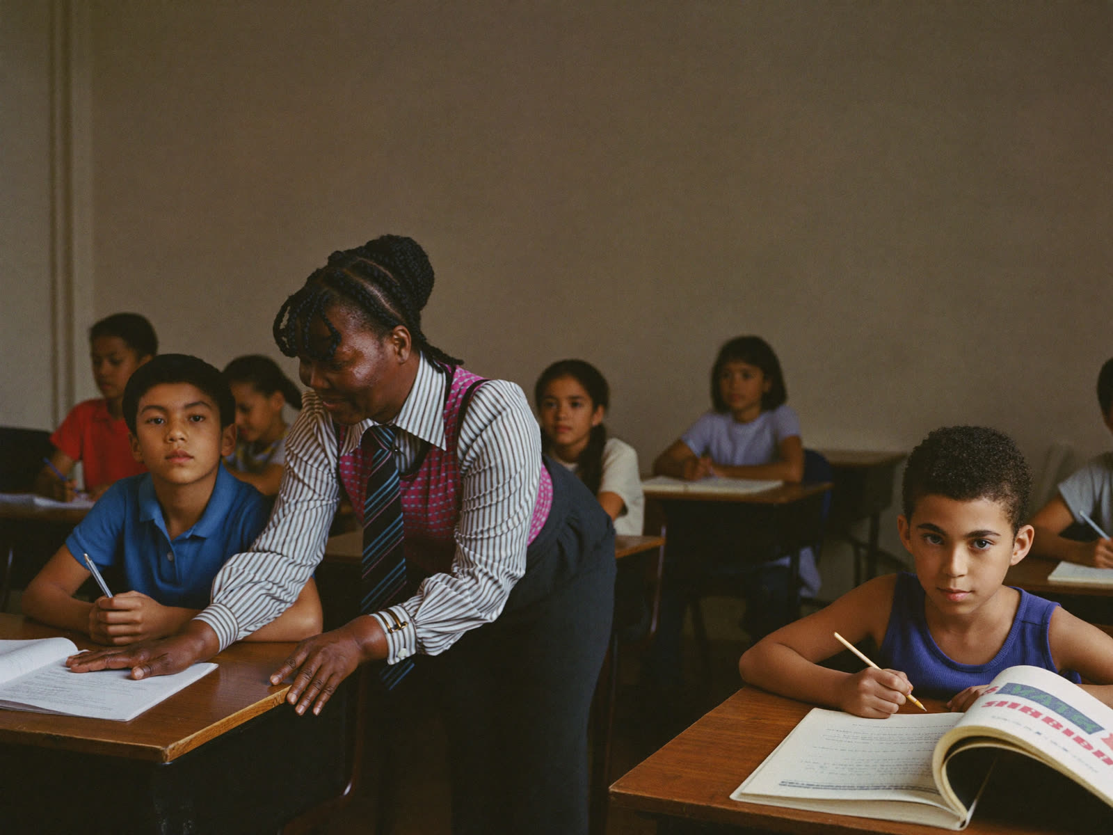 A teacher helping students at their desks in a classroom