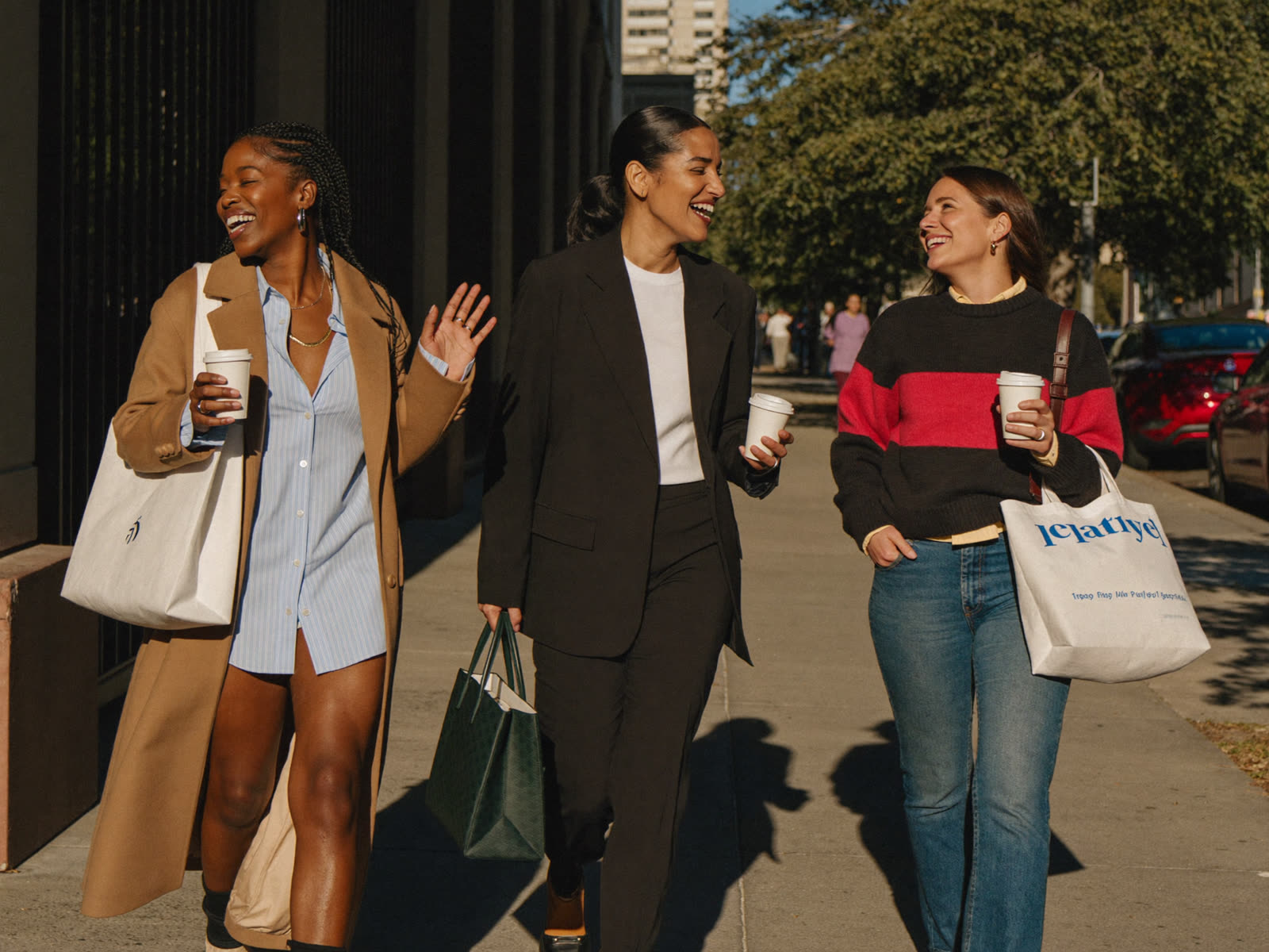 Three professional women walking together downtown with coffee