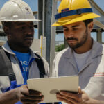 Two tradesmen reviewing plans on a tablet at a job site