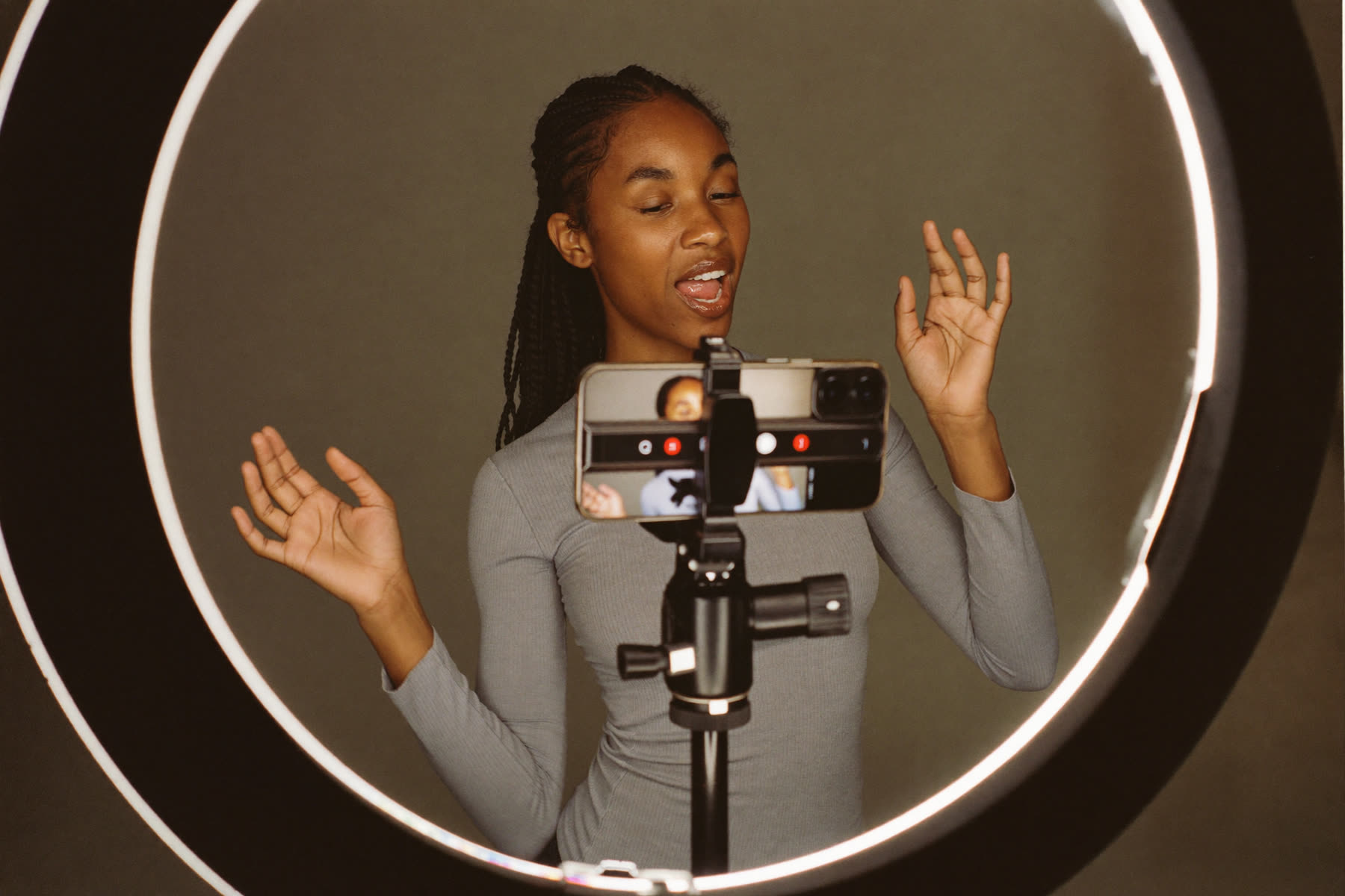 A woman filming content on her phone in a home studio