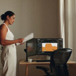 A woman reviewing market charts at a home office desk